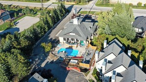 An aerial view of a residential property with a large house, a swimming pool, and a fenced yard.