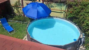 Un patio trasero con piscina, una silla de descanso azul y una sombrilla azul.