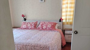 Un dormitorio con una cama, una mesita de noche, una lámpara y un cartel en la pared.
