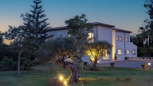 A large, white building with a tiled roof, surrounded by well-maintained gardens and trees. - Sa Roqueta – Beautiful villa with pool in the heart of Mallorca (Inca)