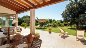 An outdoor patio with a wooden pergola, seating area, and a view of a well-maintained garden. - Sa Roqueta – Beautiful villa with pool in the heart of Mallorca (Inca)