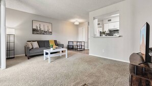 A modern living room with a grey sofa, a white coffee table, and a painting on the wall. - Pool -Gym- Great for Mid/Long Stays (Mesa)