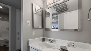 A modern bathroom with a white sink, two mirrors, a towel, and a showerhead. - Pool -Gym- Great for Mid/Long Stays (Mesa)