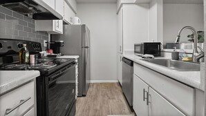 A modern kitchen with stainless steel appliances, white cabinetry, and a grey tiled backsplash. - Pool -Gym- Great for Mid/Long Stays (Mesa)