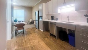 A modern kitchen with stainless steel appliances, a white countertop, and a wooden floor. - 403 Modern Brand New Studio Apartment (Old Bridge)