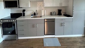 A modern kitchen with grey cabinets, a stainless steel stove, and a dishwasher. - 410 Modern Brand New Studio Apartment (Old Bridge)