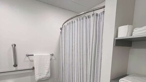 A modern bathroom with a shower curtain, towel rack, toilet paper, and a Revlon box. - 410 Modern Brand New Studio Apartment (Old Bridge)