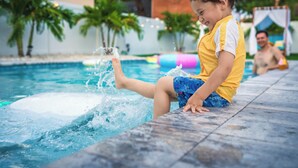 Un enfant joue dans une piscine, l’eau éclabousse tout autour de lui.