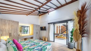 Um quarto espaçoso com uma cama grande, um ventilador de teto e vista para uma varanda.