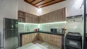 Uma cozinha moderna com geladeira de aço inoxidável, micro-ondas, fogão e armários de madeira.