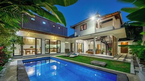 Uma casa moderna com piscina, um alpendre coberto e uma escadaria para o andar superior.