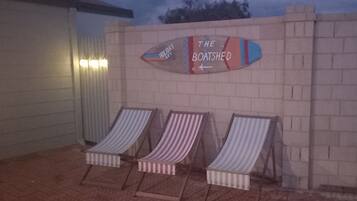 A beachside area with a sign reading "The Boathouse" and three striped lounge chairs.