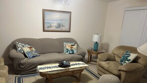 Ein Wohnzimmer mit einer Couch, Sesseln, einem Couchtisch und einer Lampe.