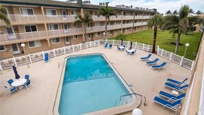 Ein Hotel mit Swimmingpool, Liegestühlen und einem eingezäunten Deckbereich.