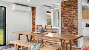 Cocina moderna con pared de ladrillo decorativa, mesa de madera con bancos y vistas al exterior.
