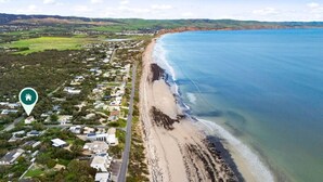 Vista aérea de una zona costera con playa, casas y una carretera.