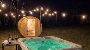 Ett bubbelbad med en trädeck, ett bord med en flaska och glas, och ljusslingor.