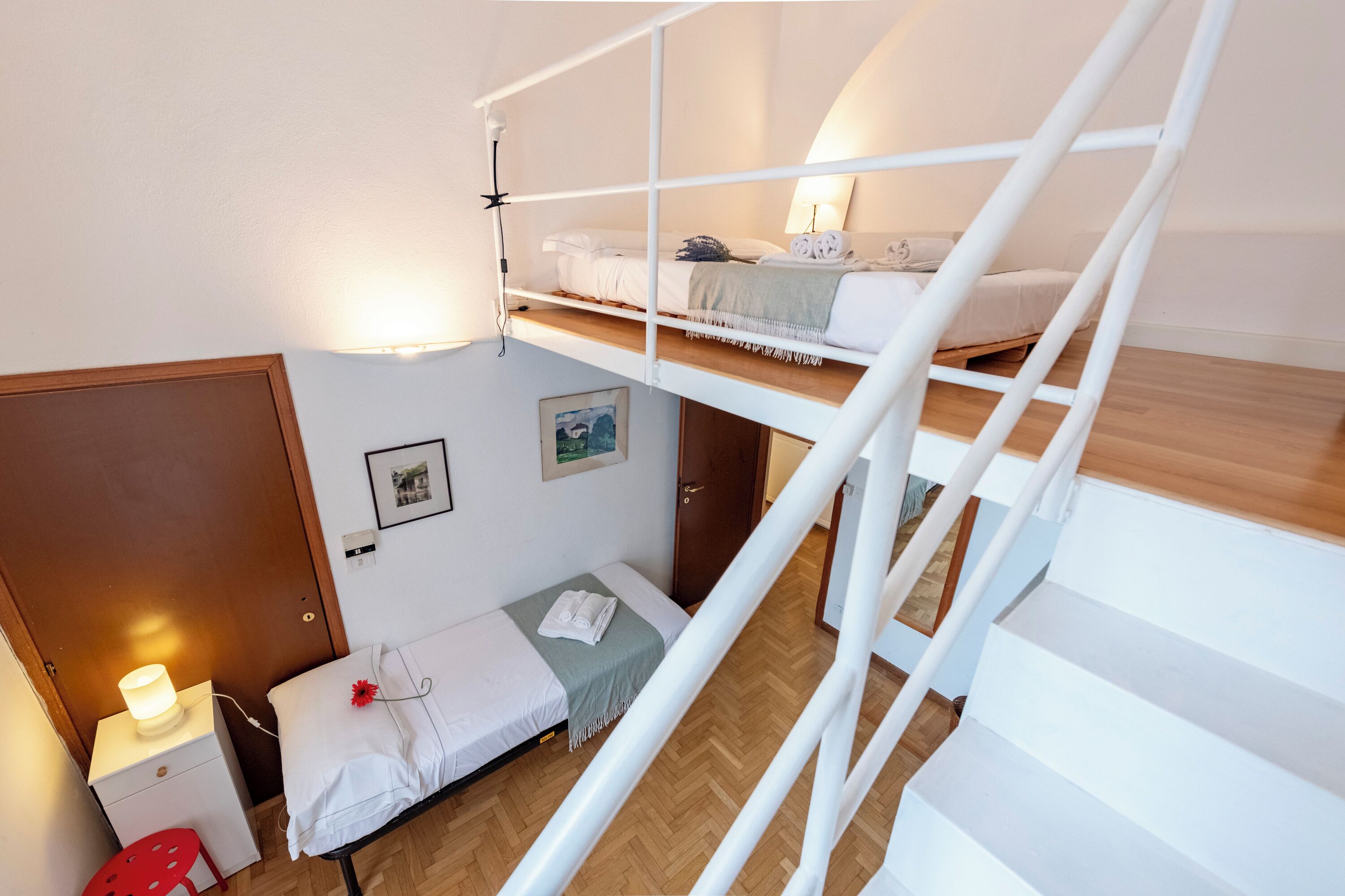 Et sovesalsværelse med køjesenge, et skrivebord, en stol og et lille bord med en lampe.