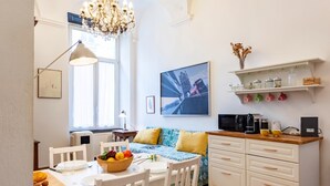 Una cocina moderna con armarios blancos, una mesa de comedor con sillas, una araña y un ventanal grande.