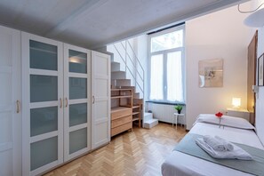 Une chambre à coucher avec un lit, une armoire, un escalier et une fenêtre.