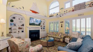 A spacious living room with a fireplace, comfortable seating, and nautical decor.