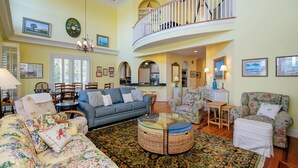 A spacious living room with a blue sofa, floral armchairs, a round coffee table, and a large rug.