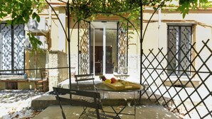 A patio area with a metal table, a bench, and a glass door leading to an interior space. - Maisonette Apartment with Outdoor Dining, Genova, Italy (Genova)