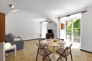 A dining area with a round table, four chairs, and a television in the background.