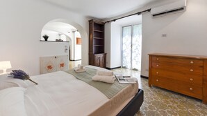 A bedroom with a bed, a dresser, a wardrobe, a mirror, and a door leading to another room. - Maisonette Apartment with Outdoor Dining, Genova, Italy (Genova)