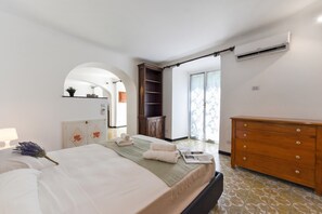 Ein Schlafzimmer mit einem Bett, einem Schminktisch, einem Kleiderschrank, einem Spiegel und einer Tür zu einem anderen Raum.