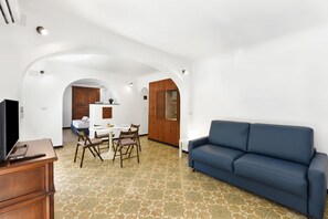 Un intérieur moderne comprenant un coin repas, un canapé et un téléviseur posé sur un meuble en bois.