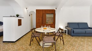 A dining area with a round table, four chairs, and a blue sofa. - Maisonette Apartment with Outdoor Dining, Genova, Italy (Genova)