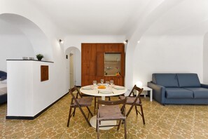 Ein Essbereich mit einem runden Tisch, vier Stühlen und einem blauen Sofa.