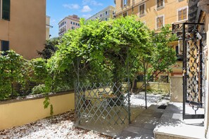 A courtyard with a pergola covered in greenery, a metal fence, and a tiled floor. - Maisonette Apartment with Outdoor Dining, Genova, Italy (Genova)