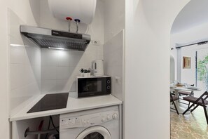 A compact kitchenette with a microwave, a coffee maker, and a built-in washing machine.