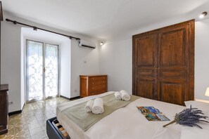 A hotel room with a bed, a wooden wardrobe, a dresser, and a window with curtains.
