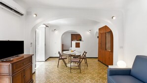 A modern living room with a flat-screen TV, a blue sofa, and a dining area with a round table and chairs. - Maisonette Apartment with Outdoor Dining, Genova, Italy (Genova)