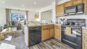 A modern kitchen with wooden cabinets, a stainless steel stove, and a dishwasher. - Whole Duplex! 3 Bedrooms, 2 Bathrooms, 4 Beds, Sleeps 8 (Colorado Springs)