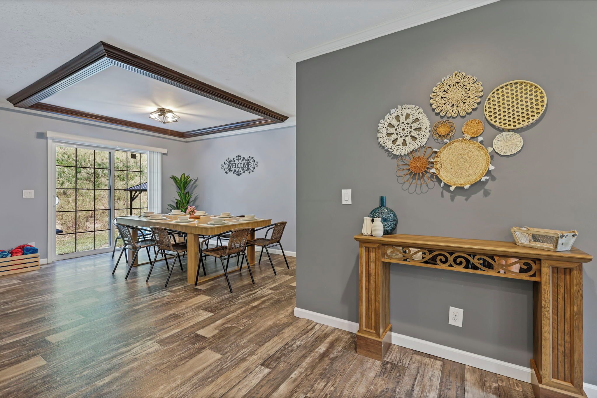 Un espace repas comprenant une table et des chaises en bois, une console ornée d’objets décoratifs et un mur agrémenté d’œuvres d’art murales de forme circulaire.