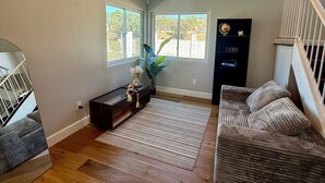 Un salon spacieux doté d’un parquet, d’un canapé marron foncé, d’un tapis à rayures et d’une grande fenêtre donnant sur l’extérieur.