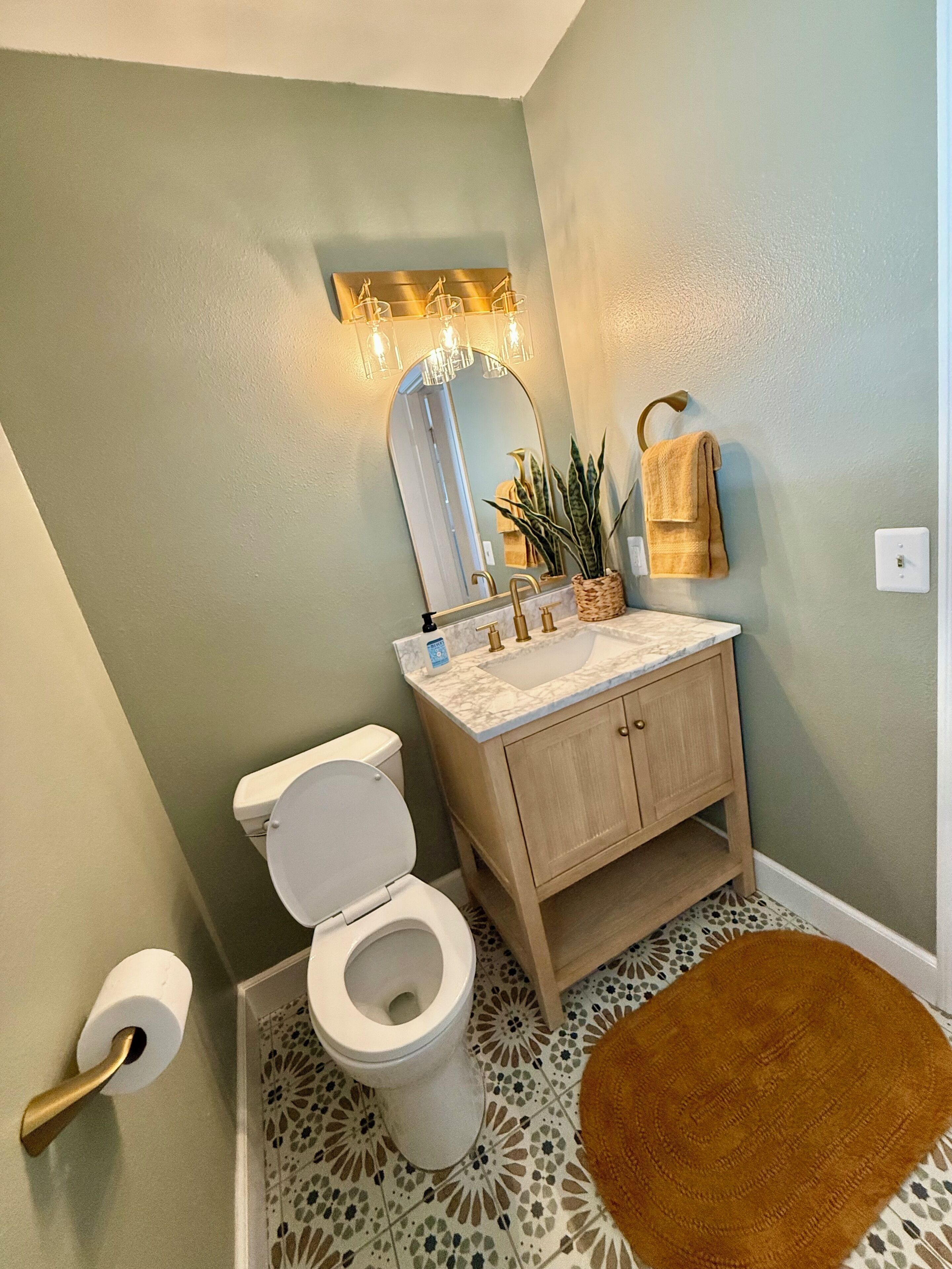 A bathroom with a toilet, sink, and mirror.