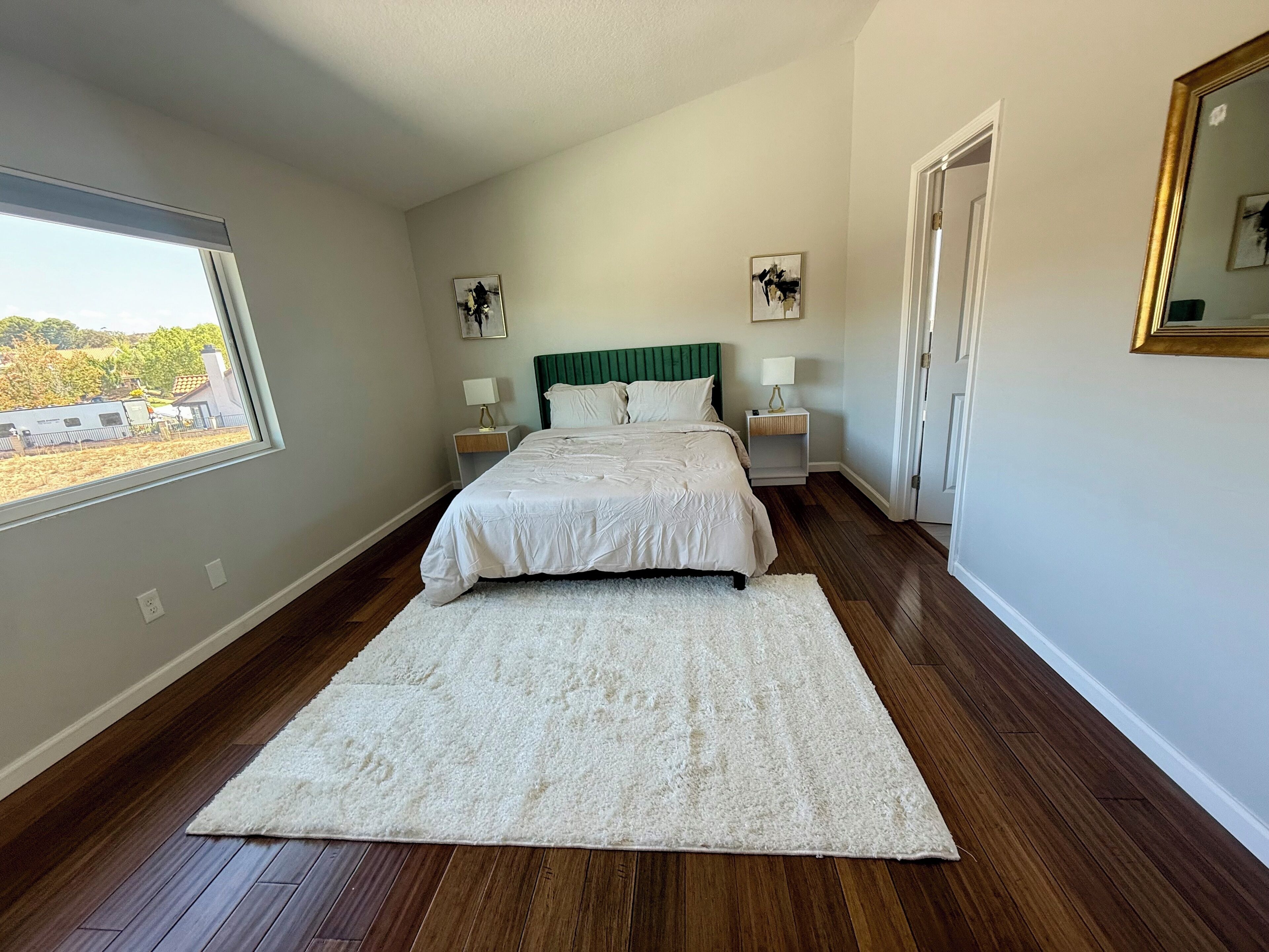 A bedroom with a large bed, two bedside tables, a window, and a door.