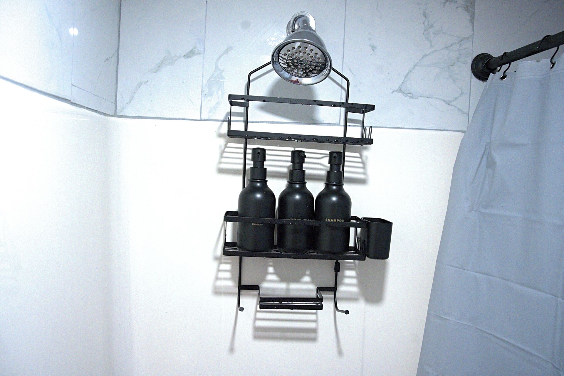 Un baño con ducha, repisa con botellas y un perchero para toallas.