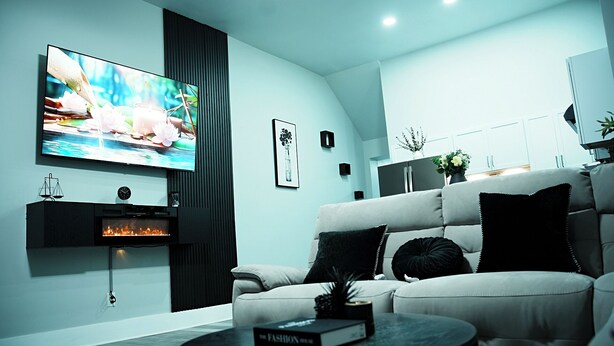 A modern living room with a flat-screen TV, a fireplace, a sofa, and a coffee table. - Modern Minimalist Home in the heart of Reading (Reading)