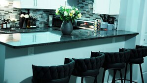 A modern kitchen with a large island, bar stools, and a coffee machine. - Modern Minimalist Home in the heart of Reading (Reading)