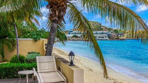 Blick auf einen Strand mit Palme, Liegestuhl und Tisch am Pool.