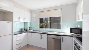 Une cuisine moderne avec des meubles blancs, un four encastré, un four à micro-ondes et un lave-vaisselle.