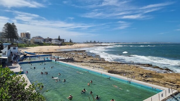 Une piscine à l’eau claire, bordée d’une côte rocheuse et d’une plage.