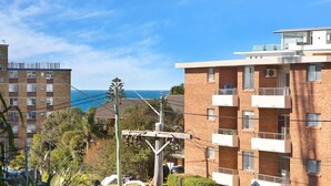 Un immeuble résidentiel à plusieurs étages, doté de balcons, offrant une vue sur l’océan et s’ouvrant sur un ciel dégagé.