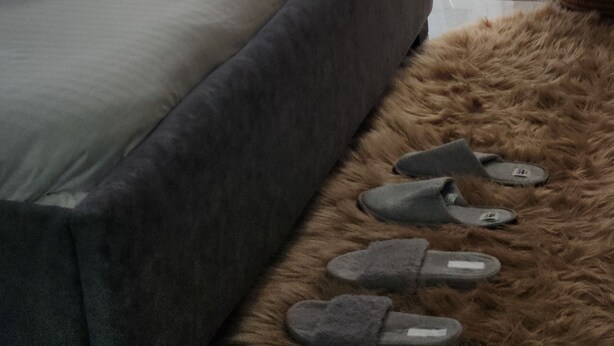 Une chambre à coucher avec un lit, un tapis moelleux et des chaussons.